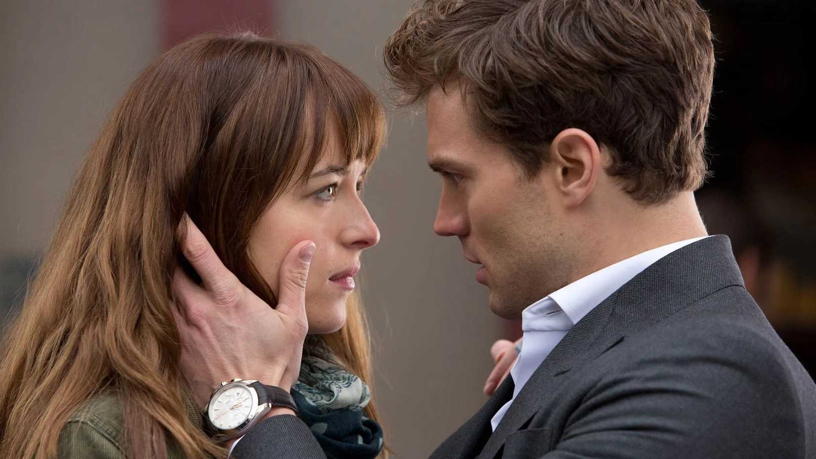 Jamie Dornan como Christian Grey segurando o rosto de Dakota Johnson como Ana em Cinquenta Tons de Cinza