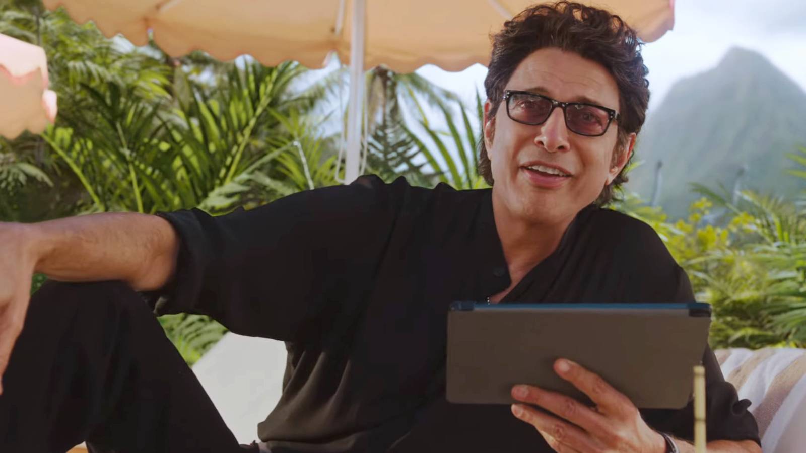 Jeff Goldblum sostiene una tableta y está sentado en su icónica pose de Jurassic Park en un comercial de Xfinity.