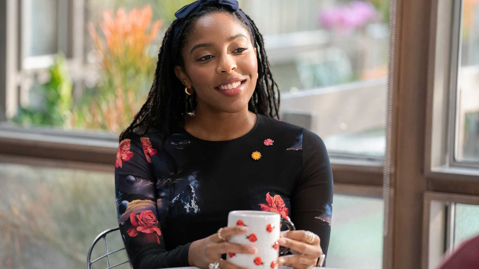 Jessica Williams als Gaby lächelt, während sie in Shrinking eine Tasse Kaffee in der Hand hält