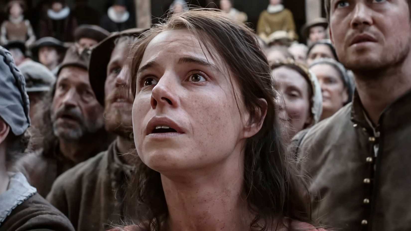 Jessie Buckley looking up in awe surrounded by people in Hamnet