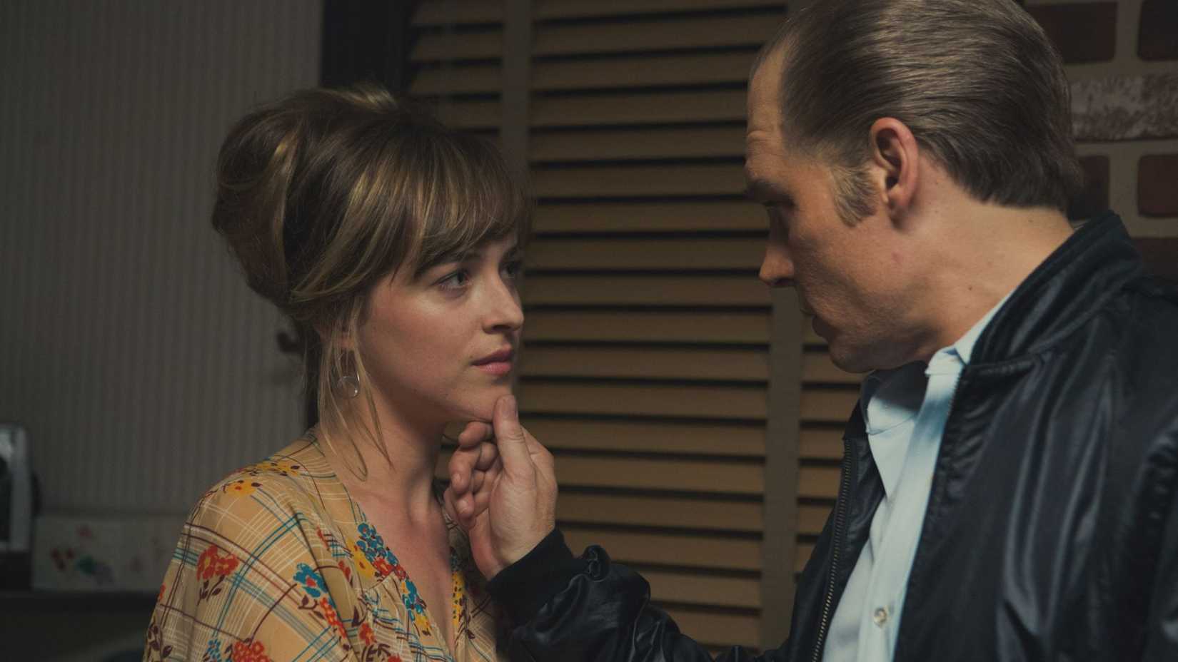 Johnny Depp como Whitey Bulger olhando para Dakota Johnson como Lindsey Cyr em Aliança do Crime