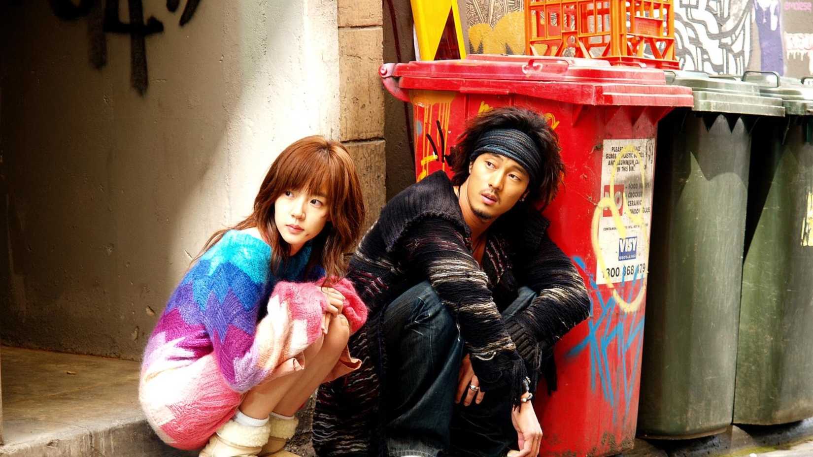 Um homem e uma mulher agachados na rua no K-Drama I'm Sorry, I Love You.