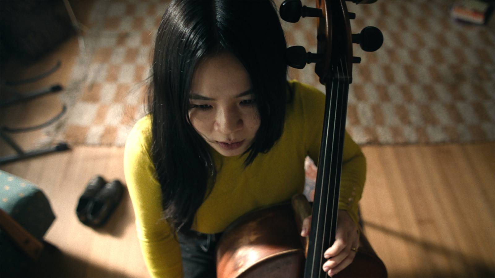 Kelly Marie Tran looking worried while holding her cello in Rock Springs