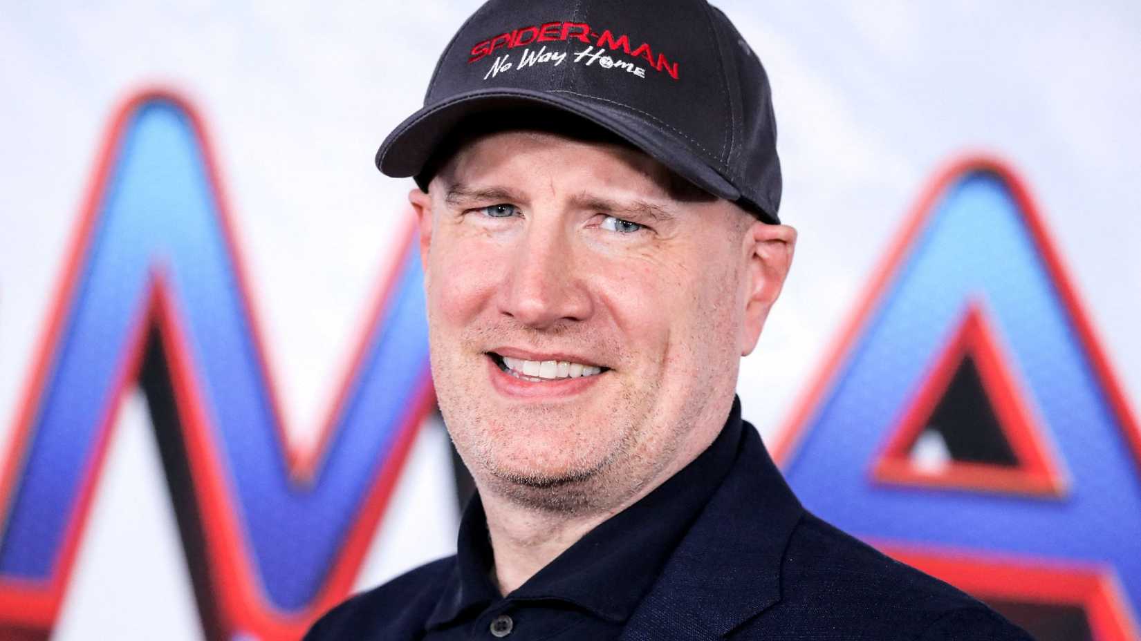 Kevin Feige from the MCU standing against a sign