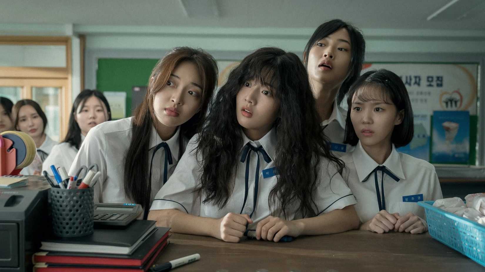 Cuatro estudiantes inclinan la cabeza mientras miran algo fuera de la pantalla en la película coreana Love Untangled.