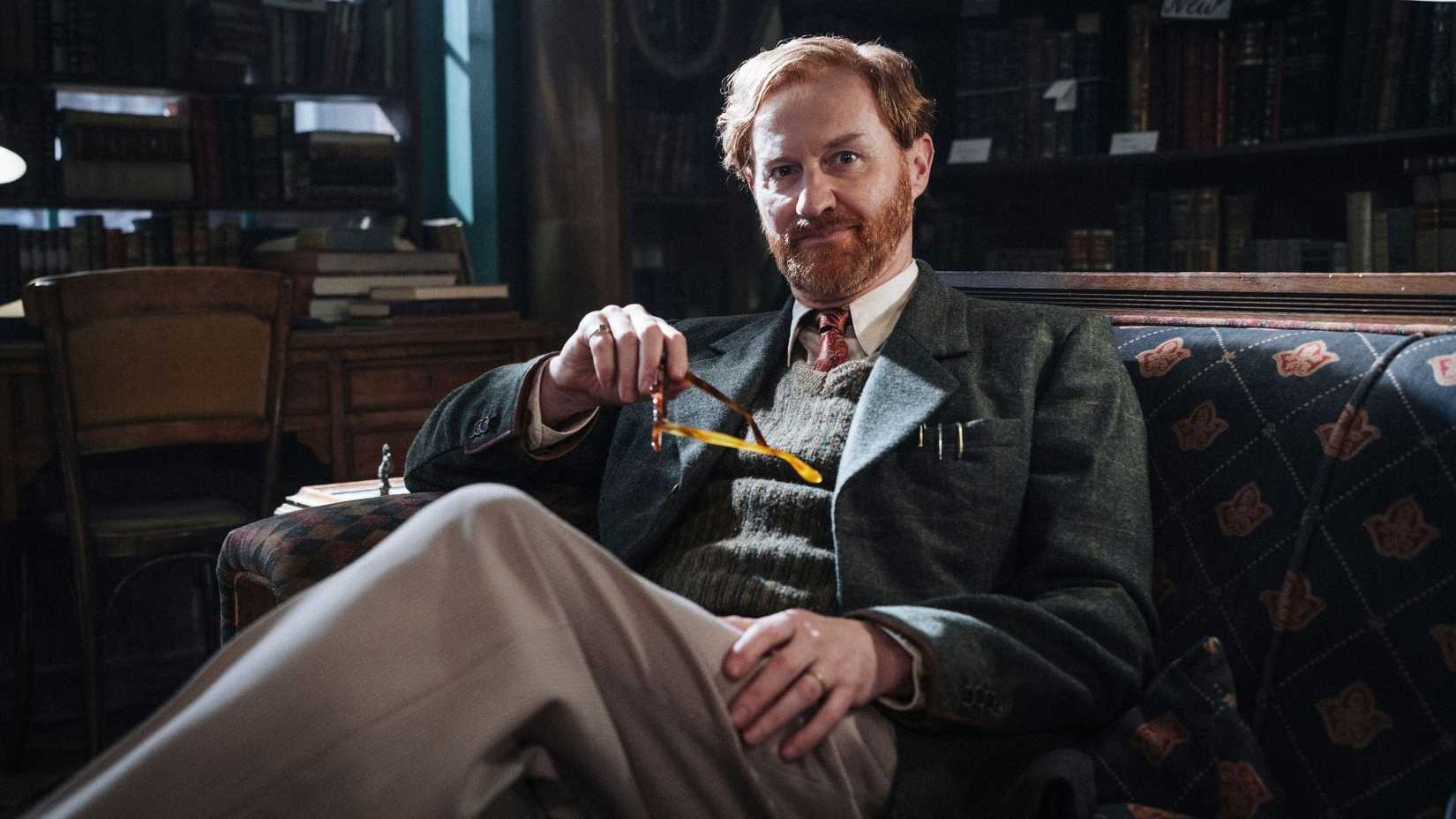 mark gatiss as gabriel book sitting down holding glasses in bookish