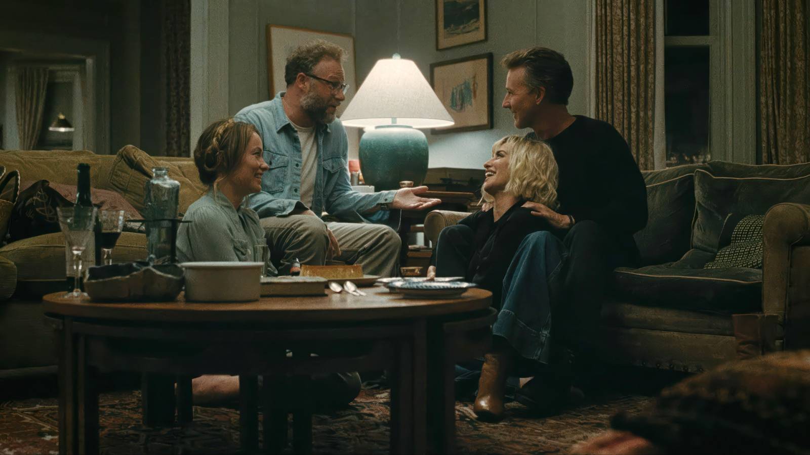 Olivia Wilde, Seth Rogen, Penelope Cruz, and Edward Norton sit close together on a couch in a living room and talk 