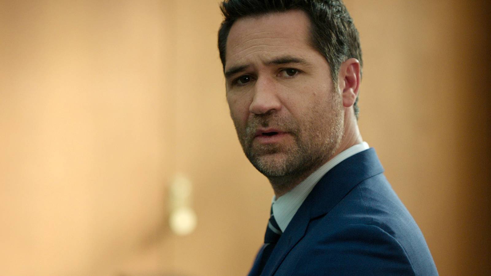 Mickey looks over his shoulder upset in The Lincoln Lawyer season 4
