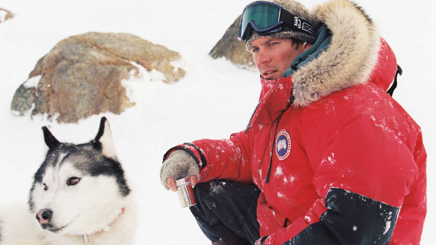 Paul Walker's Jerry leaning down in the snow next to one of the dogs in Eight Below
