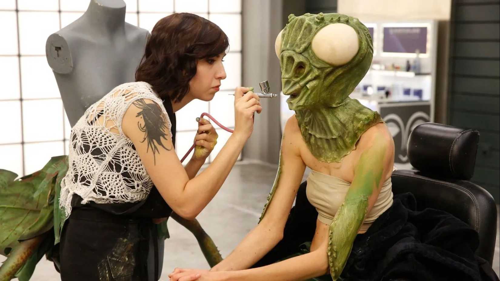 Mulher aplicando uma prótese de louva-a-deus no reality show Face Off.