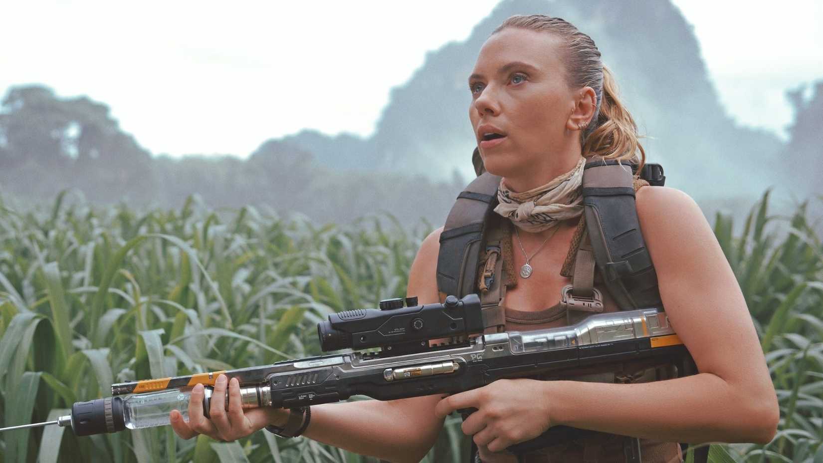 Scarlett Johansson em Jurassic World Rebirth, com dinossauros ao fundo.