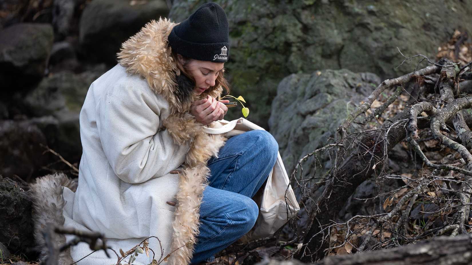 Shailene Woodley como Annie tentando se aquecer na floresta em Paradise temporada 2