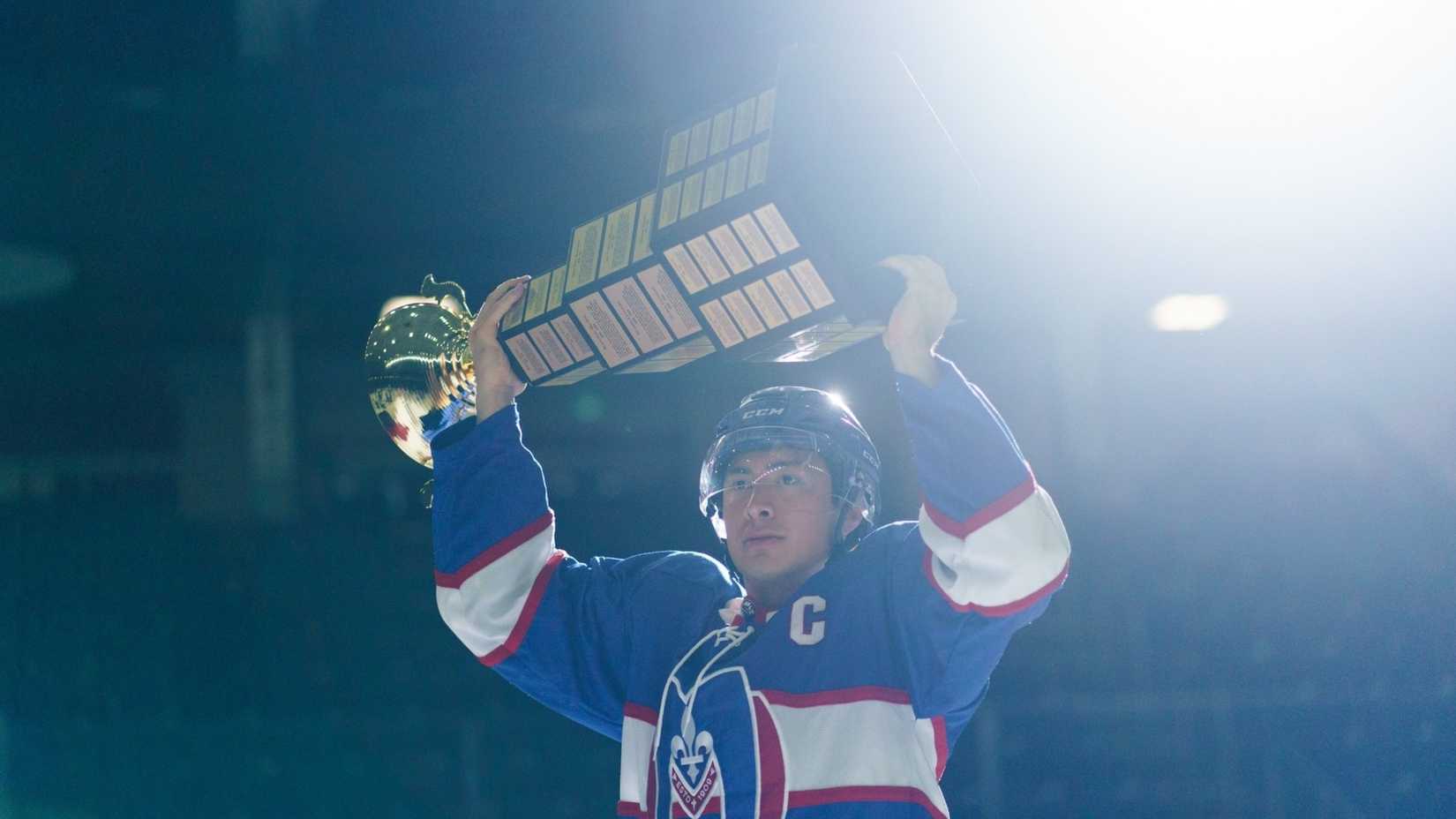 Shane Hollander (Hudson Williams) holding the Stanley Cup over his head on the ice in Heated Rivalry