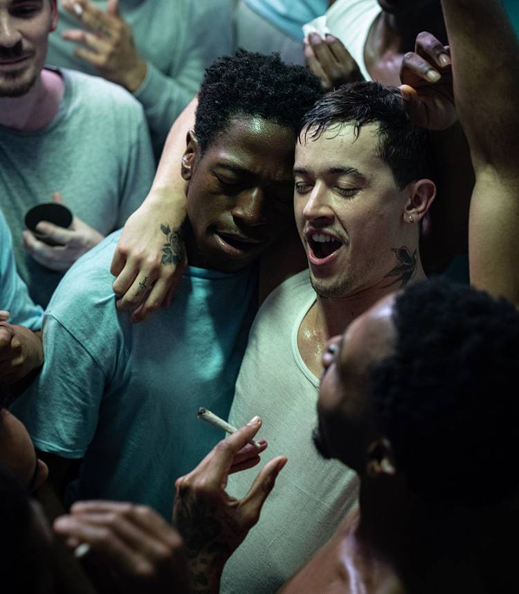 tom blyth s dee with his arm around david jonsson s taylor in the midst of a party crowd in wasteman