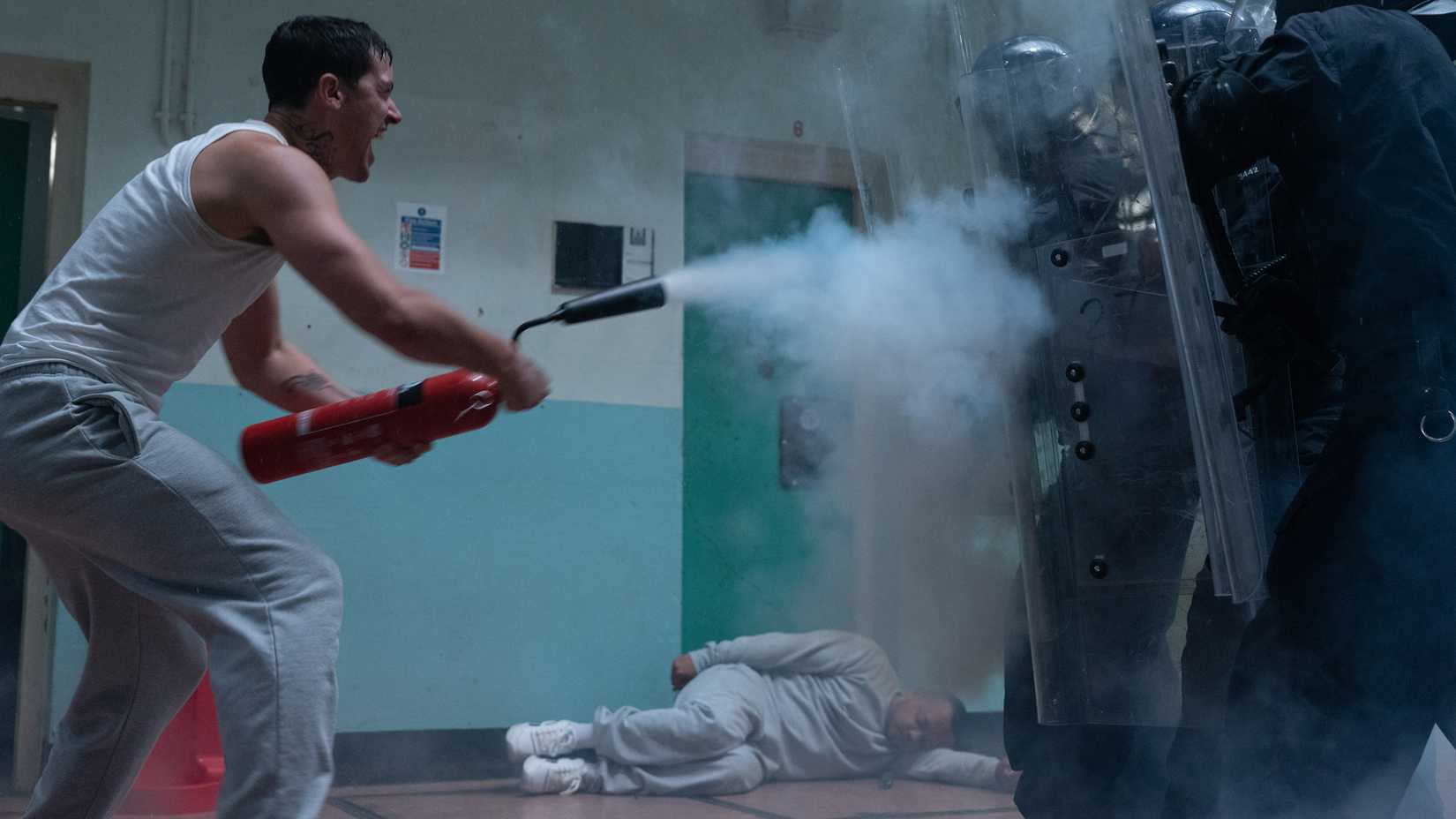 tom blyth s taylor shooting a fire extinguisher at riot guards in wasteman