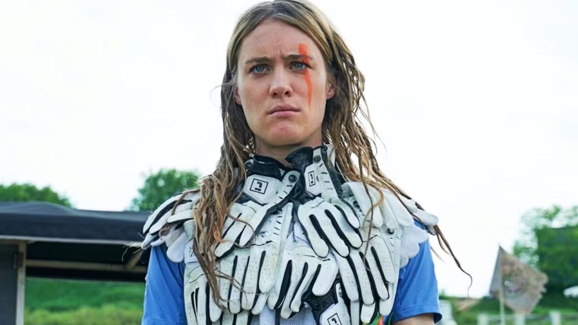 Mackenzie Davis als Kirsten in Station Eleven blickt streng in einer Weste aus Handschuhen zu