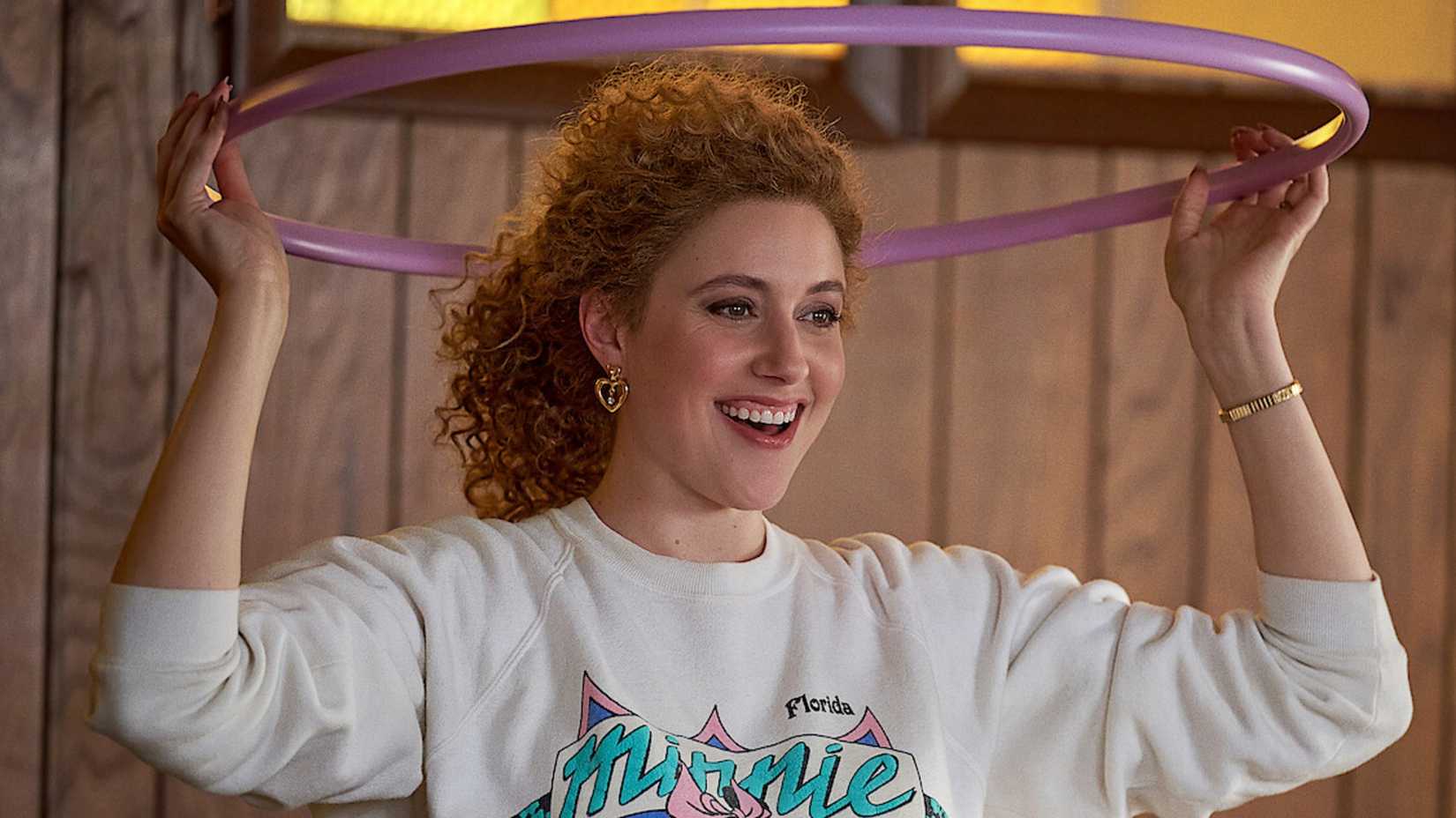 Greta Gerwig holds a hula hoop above her head in White Noise