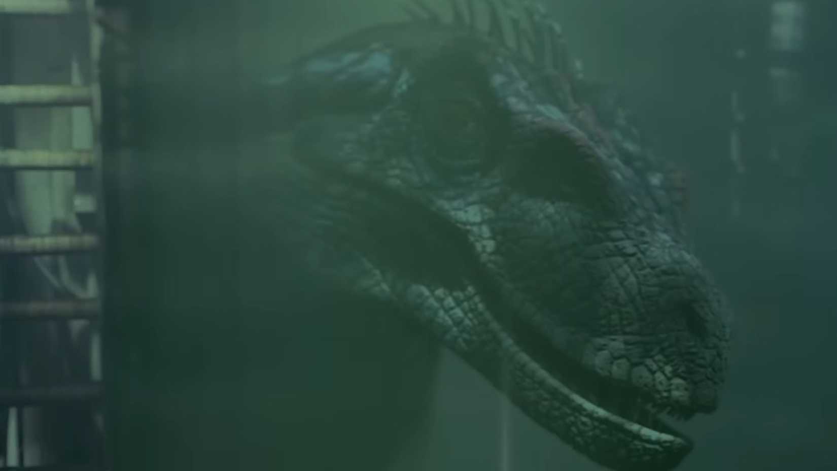 Um raptor parado atrás de uma grande câmara de teste em Jurassic Park 3