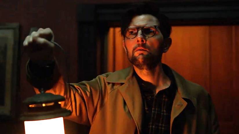 Ohm (Adam Scott) preocupado segurando uma lanterna em Hokum