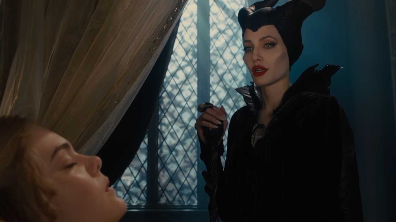 Angelina Jolie como Malévola em pé sobre Aurora enquanto ela dorme.