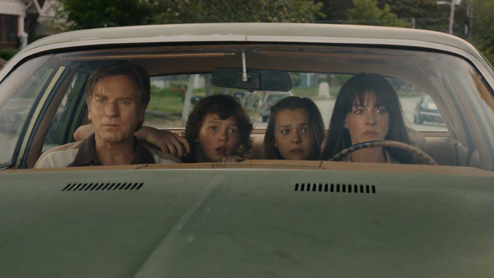 anne hathaway and ewan mcgregor sit in a car with their kids in the end of oak street 1
