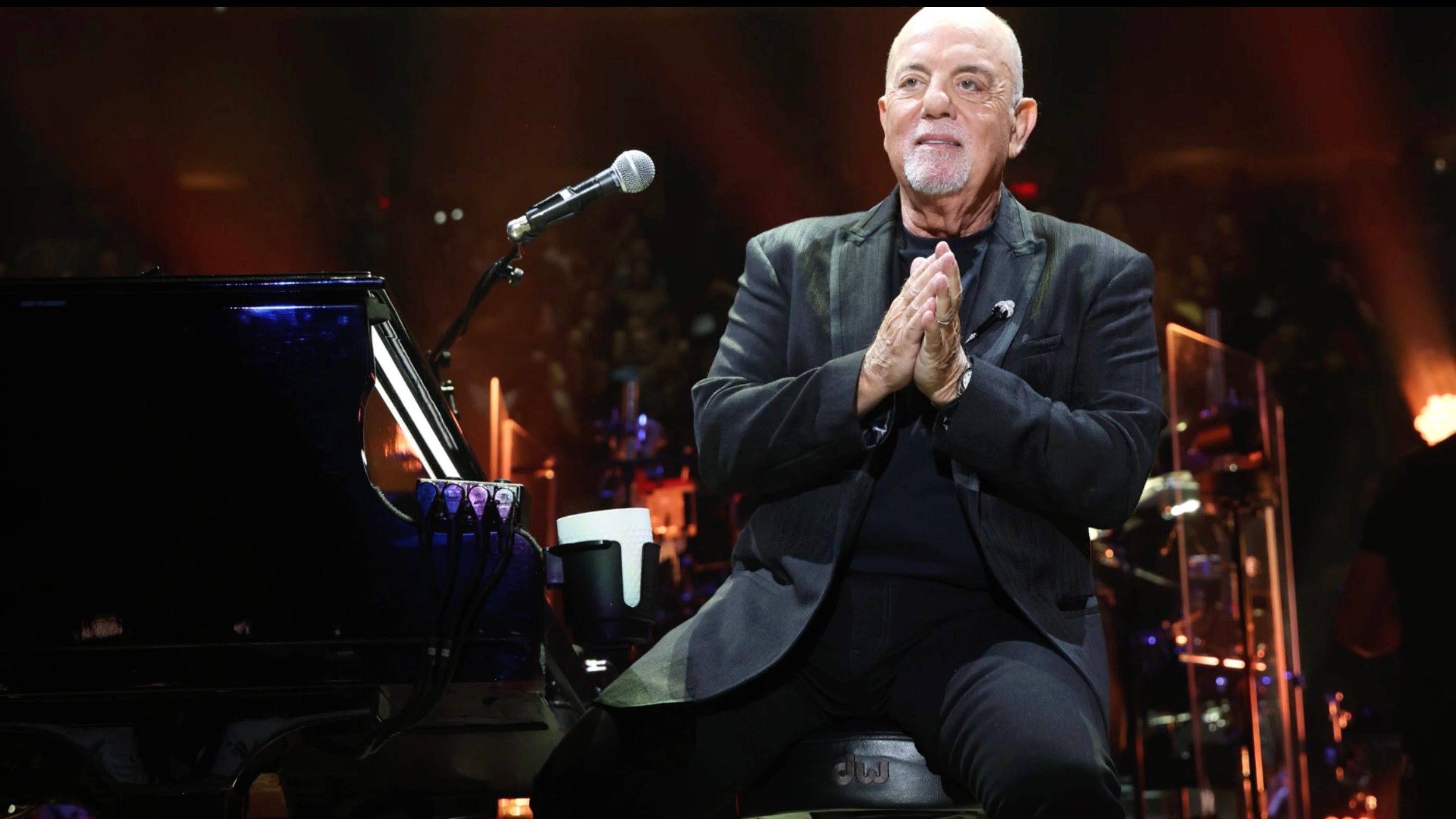 Billy_JoelClassic rock legend Billy Joel looking contemplative on stage with a piano during a tribute performance.