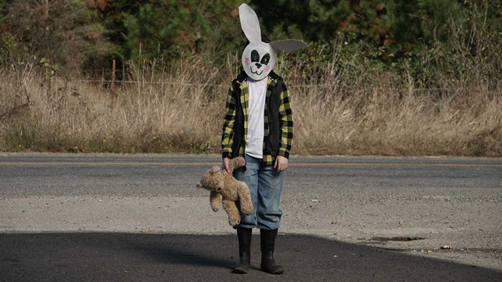 Garoto com máscara de coelho de papel olhando para a câmera no remake de 2016 de Cabana do Inferno
