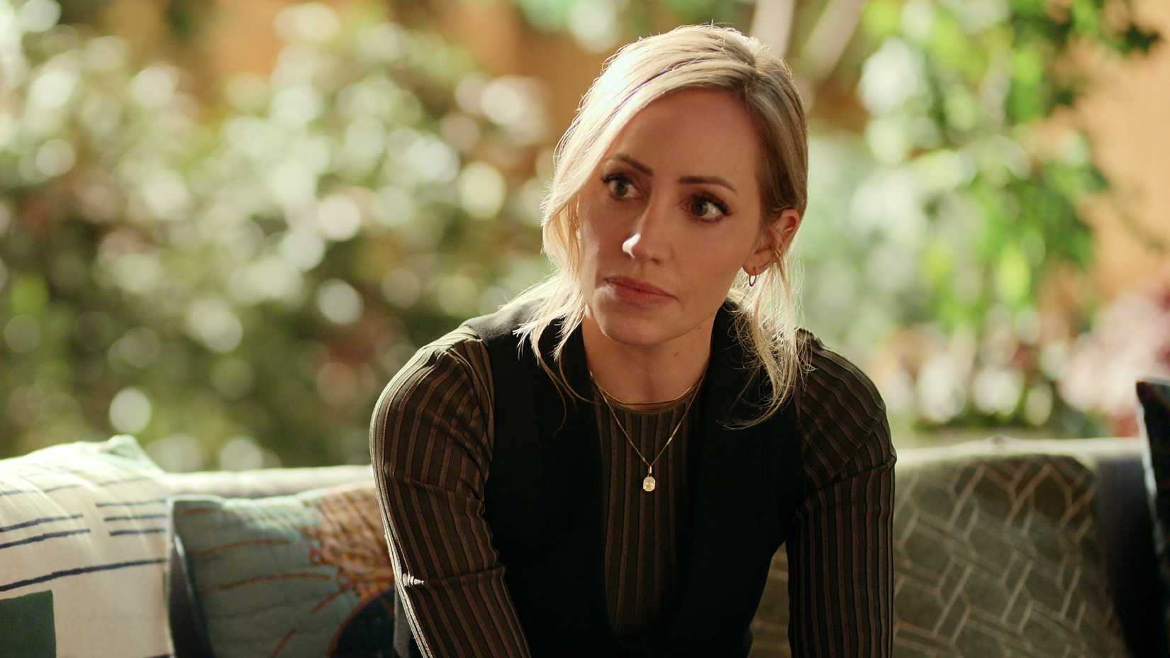 Brie Sheridan looks to the side upset whille sitting outside in Virgin River season 7 episode 1