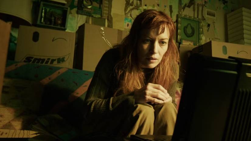 Britt Lower huddled in front of a computer surrounded by boxes in Sender