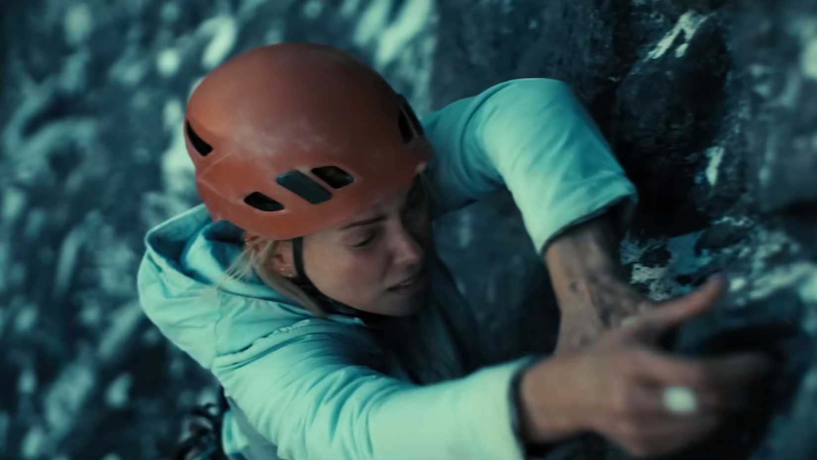 Charlize Theron como Sasha escalando uma montanha usando capacete em Apex