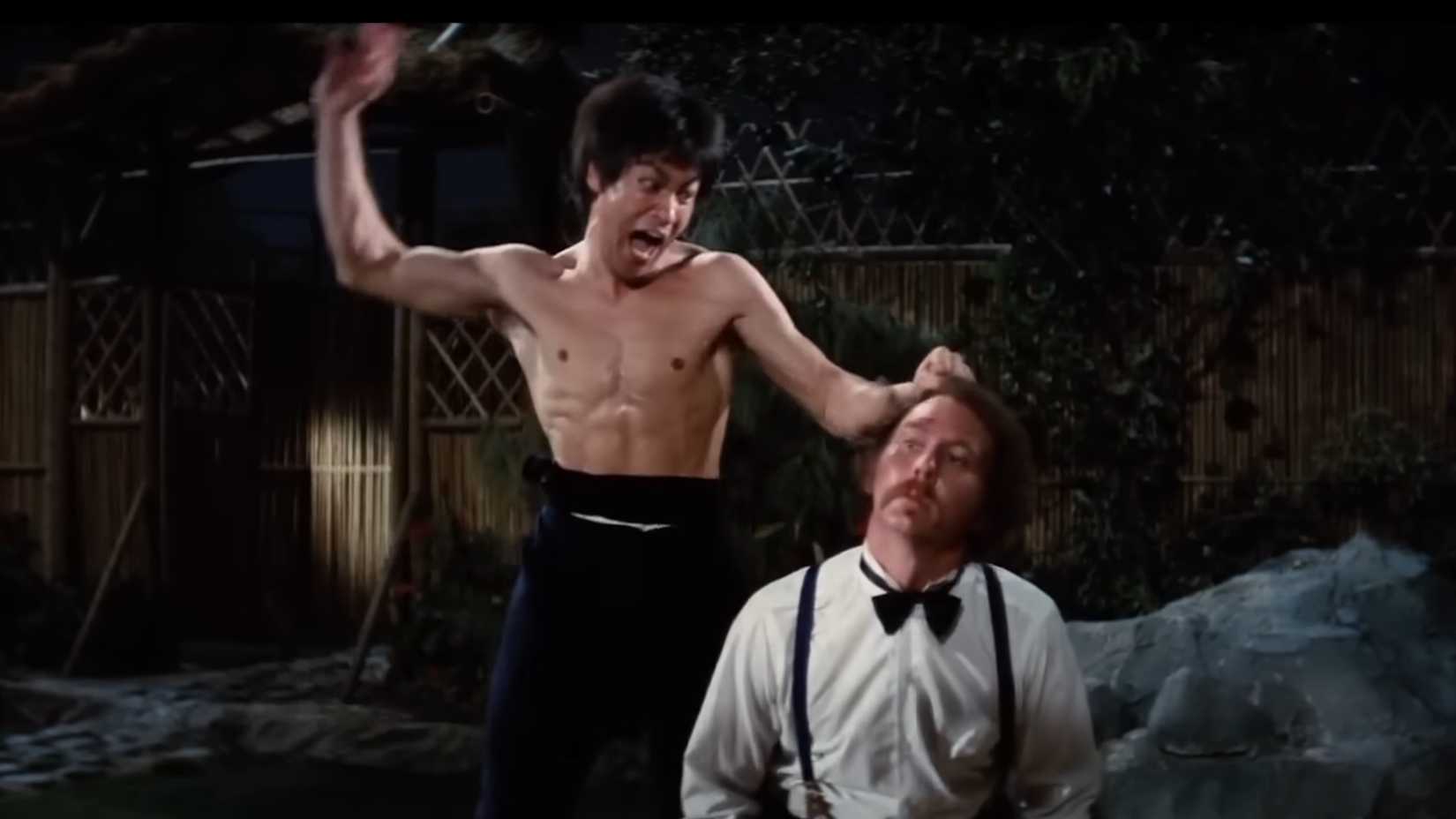 Chen Zhen (Bruce Lee) prestes a desferir o golpe fatal contra Petrov (Robert Baker) em Fúria de Titãs