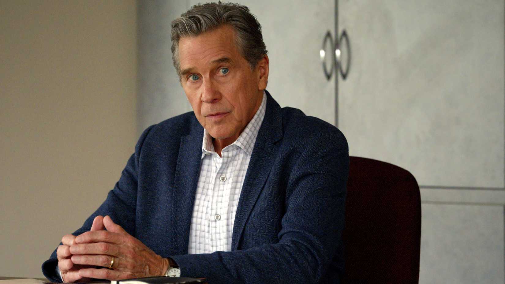 Doc Mullins sits at a table and looks to the side in Virgin River season 7 episode 7