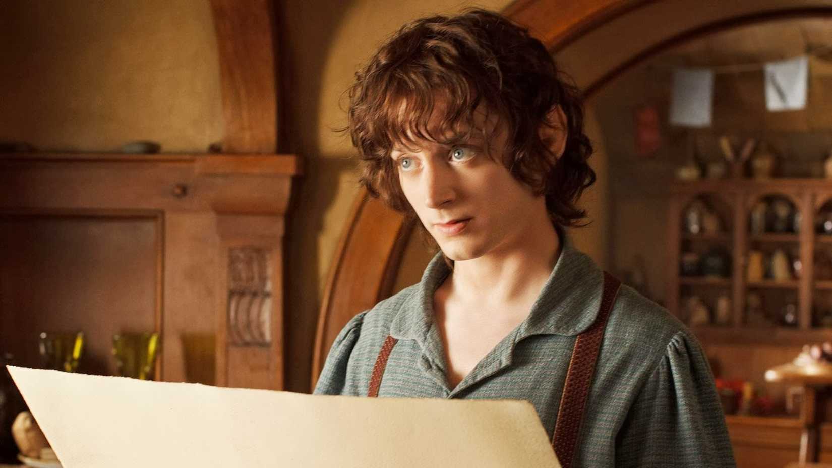Elijah Wood looking up from a large map in The Hobbit An Unexpected Journey