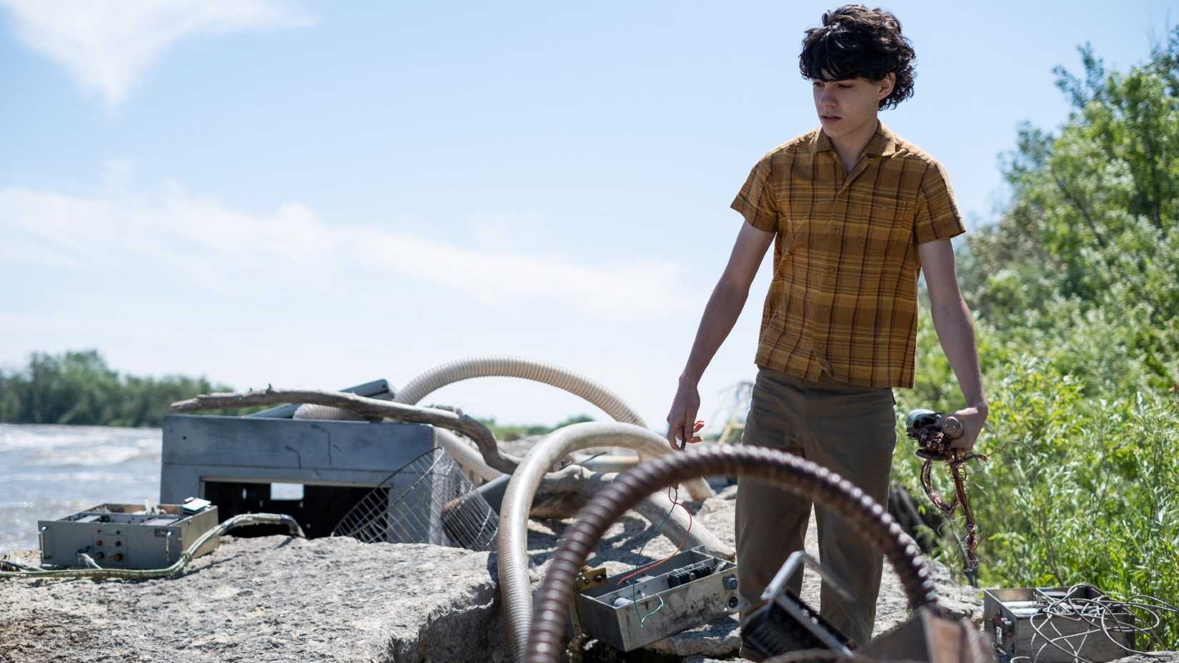 Young George (Emjay Anthony) picking up old equipment in Tales from The Loop