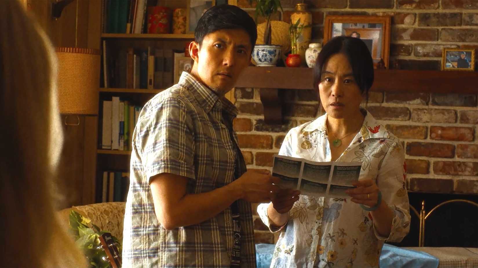 Fang Du and Vivian Wu looking confused while holding a pamphlet in Slanted