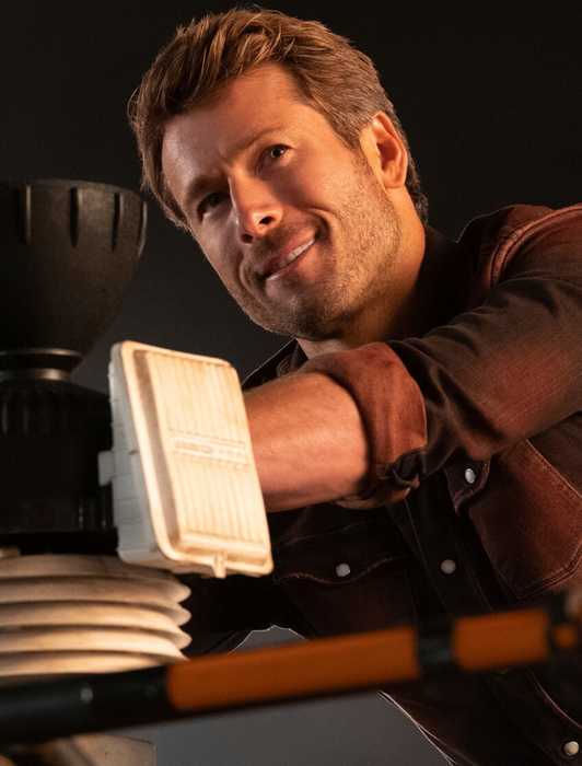 Glen Powell fixing a machine in Twisters
