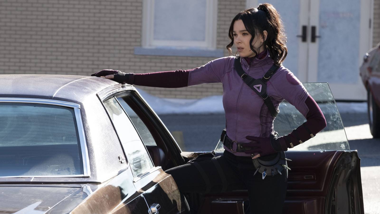 Hailee Steinfeld as Kate Bishop with her hand on top of a car in Hawkeye