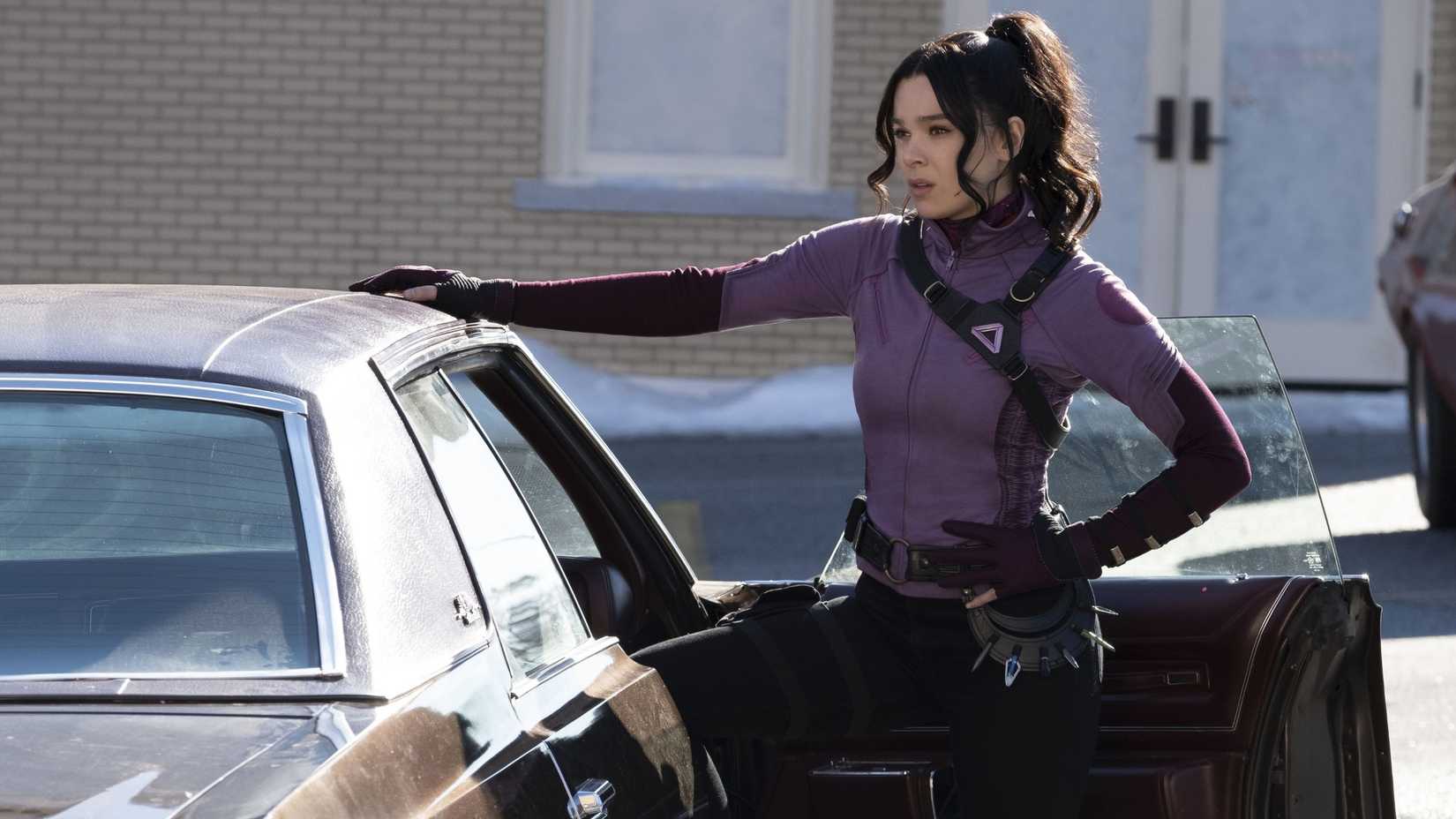 Hailee Steinfeld como Kate Bishop com a mão sobre um carro em Hawkeye