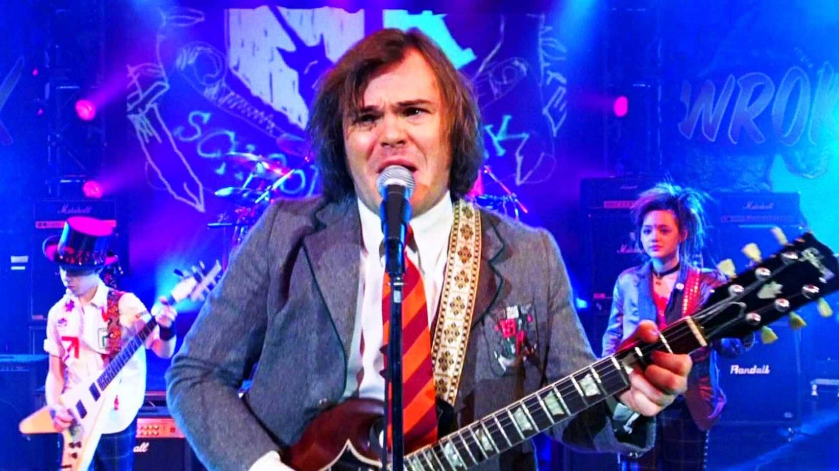 Jack Black como Dewey Finn tocando guitarra no palco em Escola de Rock