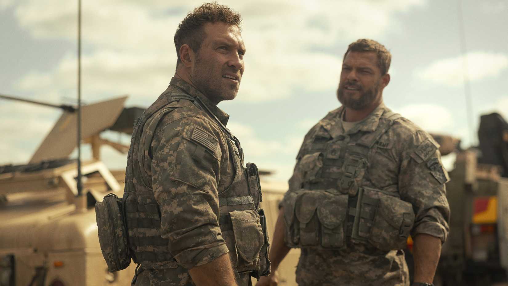 Jai Courtney stares off into the distance as Alan Ritchson talks to him in a scene from War Machine.