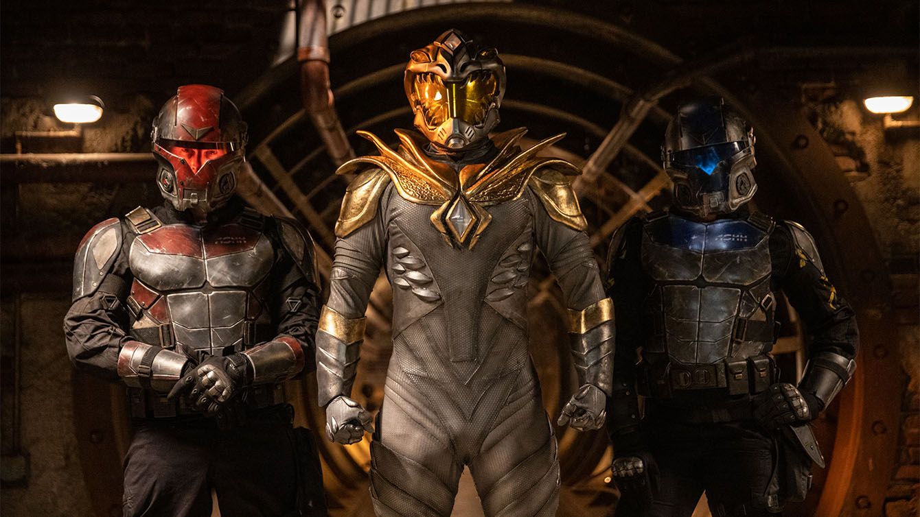 Jason David Frank como el Dragón Blanco flanqueado por personas con armadura roja y azul en Legend of the White Dragon