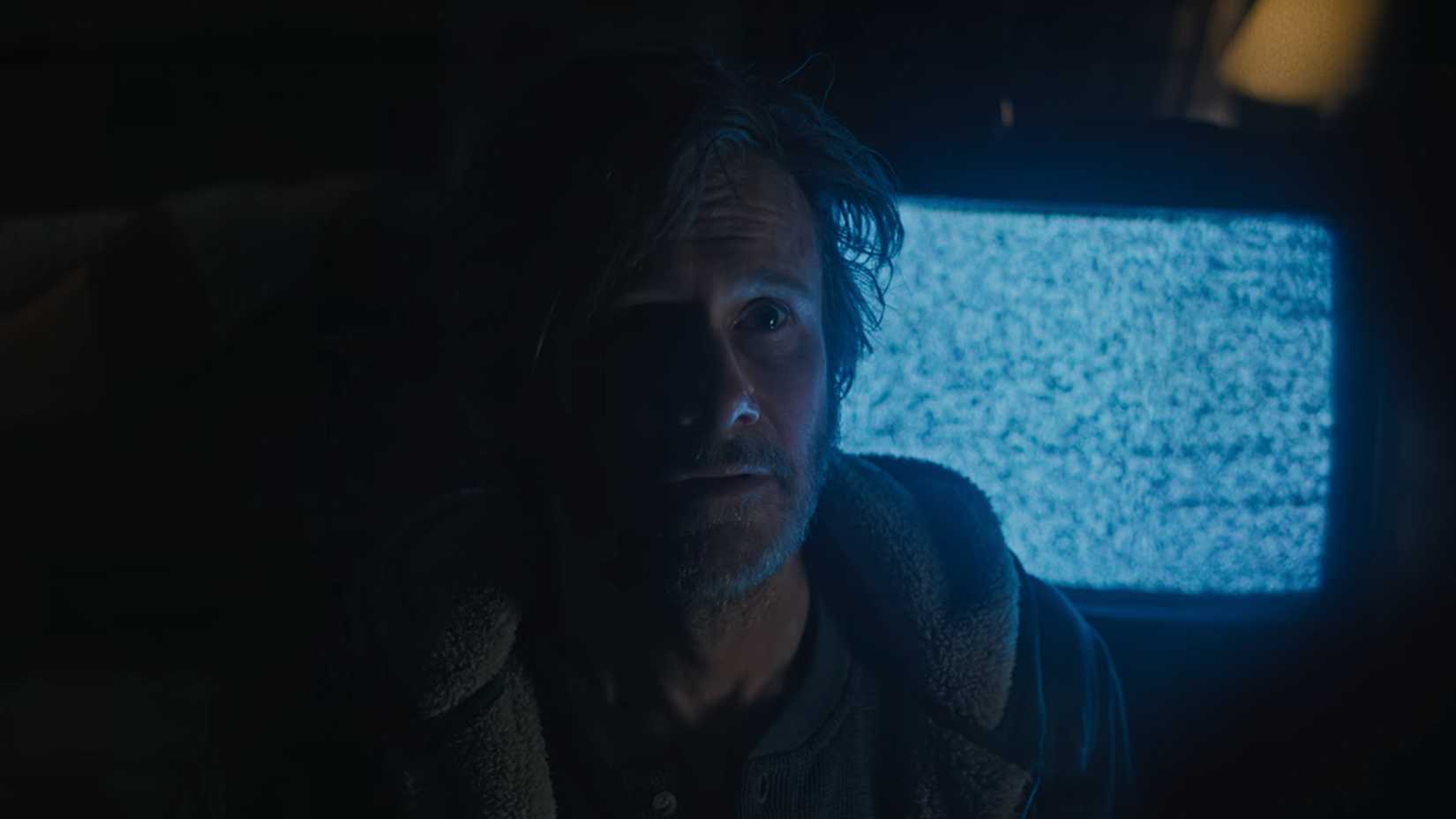 Jay Harkin stands in front of a TV with static in Something Very Bad Is Going to Happen