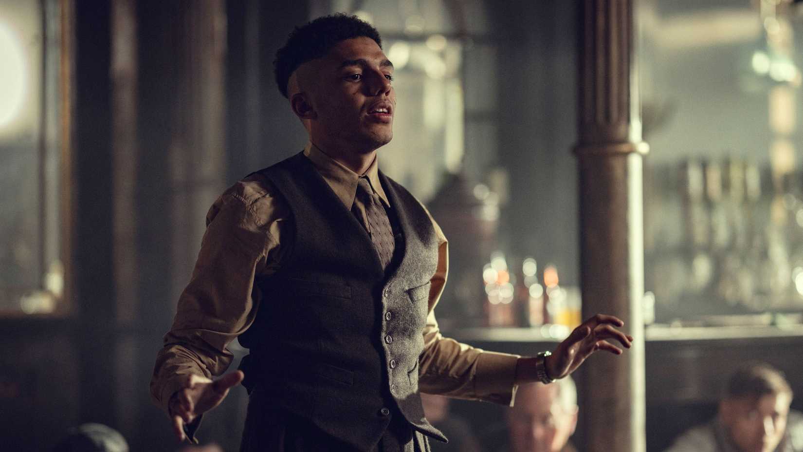 Peaky Blinders: The Immortal Man Cast Guide 7 Jay Lycurgo as Elijah standing in the Garrison trying to calm everyone down in Peaky Blinders: The Immortal Man