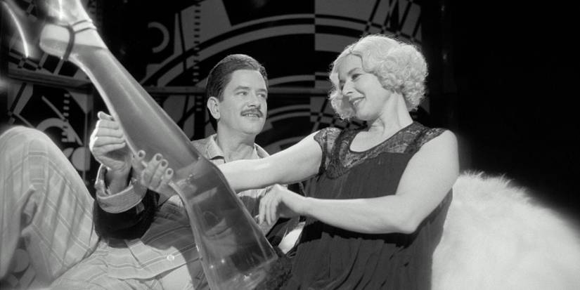 Lady Helen Port-Huntley ergue a perna cheia de cerveja enquanto olha para um homem em The Saddest Music in the World