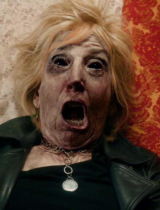 Lin Shaye as a corpse with a gaping mouth on a chair in Scared to Death