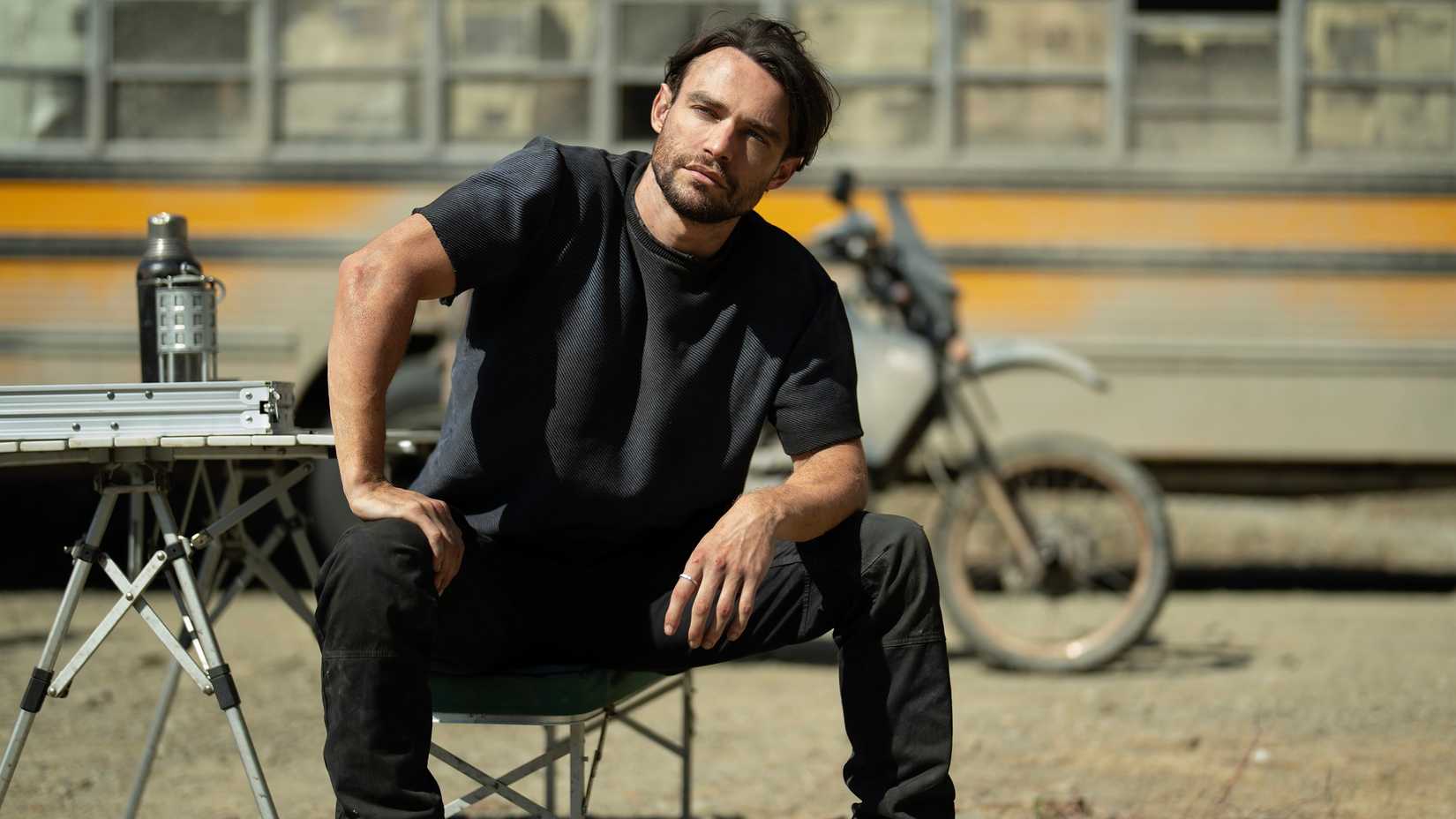 How President Bradford Foreshadowed The Bunker’s Fate 1 Thomas Doherty as Link sitting down in front of a bus and a bike in Paradise season 2