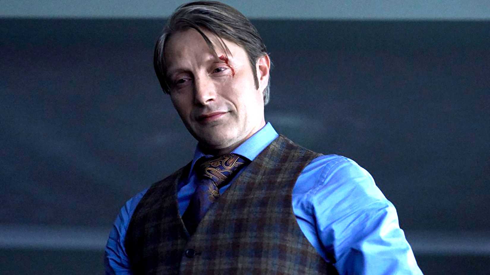 Mads Mikkelsen's Hannibal smiling ominously with a cut above his left eye in Hannibal
