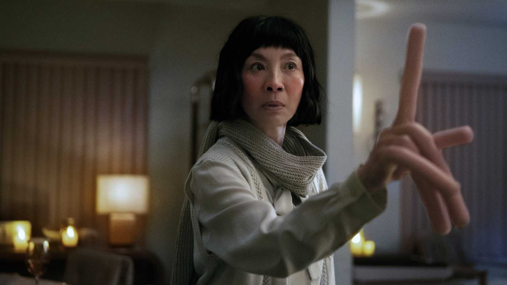 Michelle Yeoh erguendo um dos dedos de salsicha em Everything Everywhere All at Once