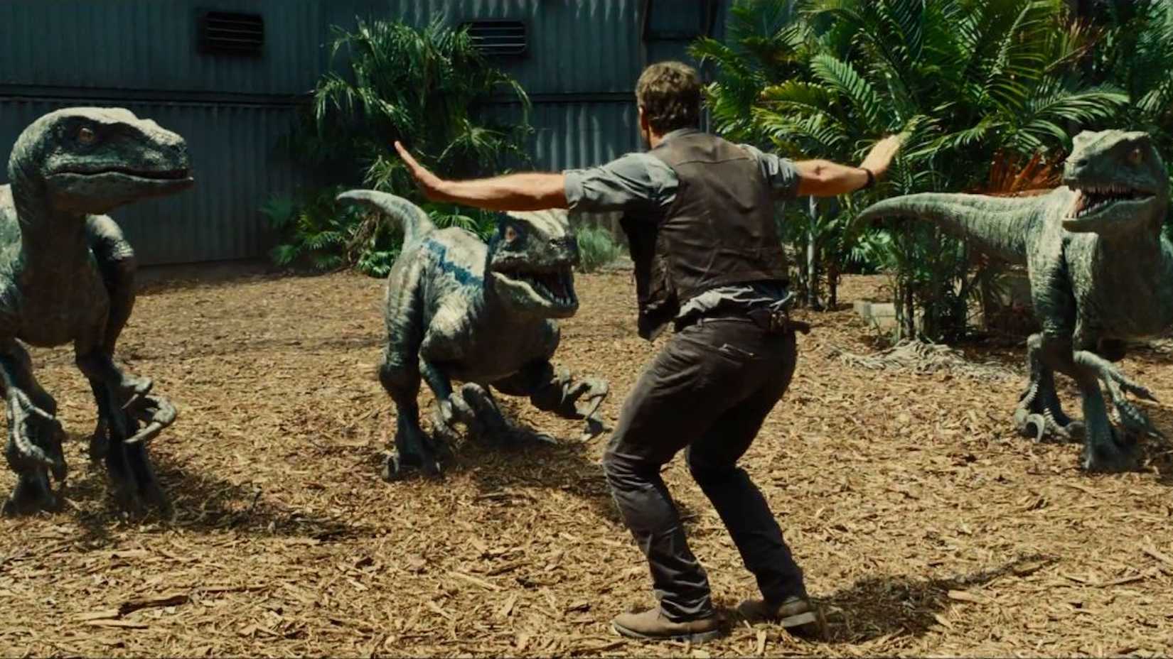 Owen (Chris Pratt) surrounded by three raptors with his arms outstretched in Jurassic World