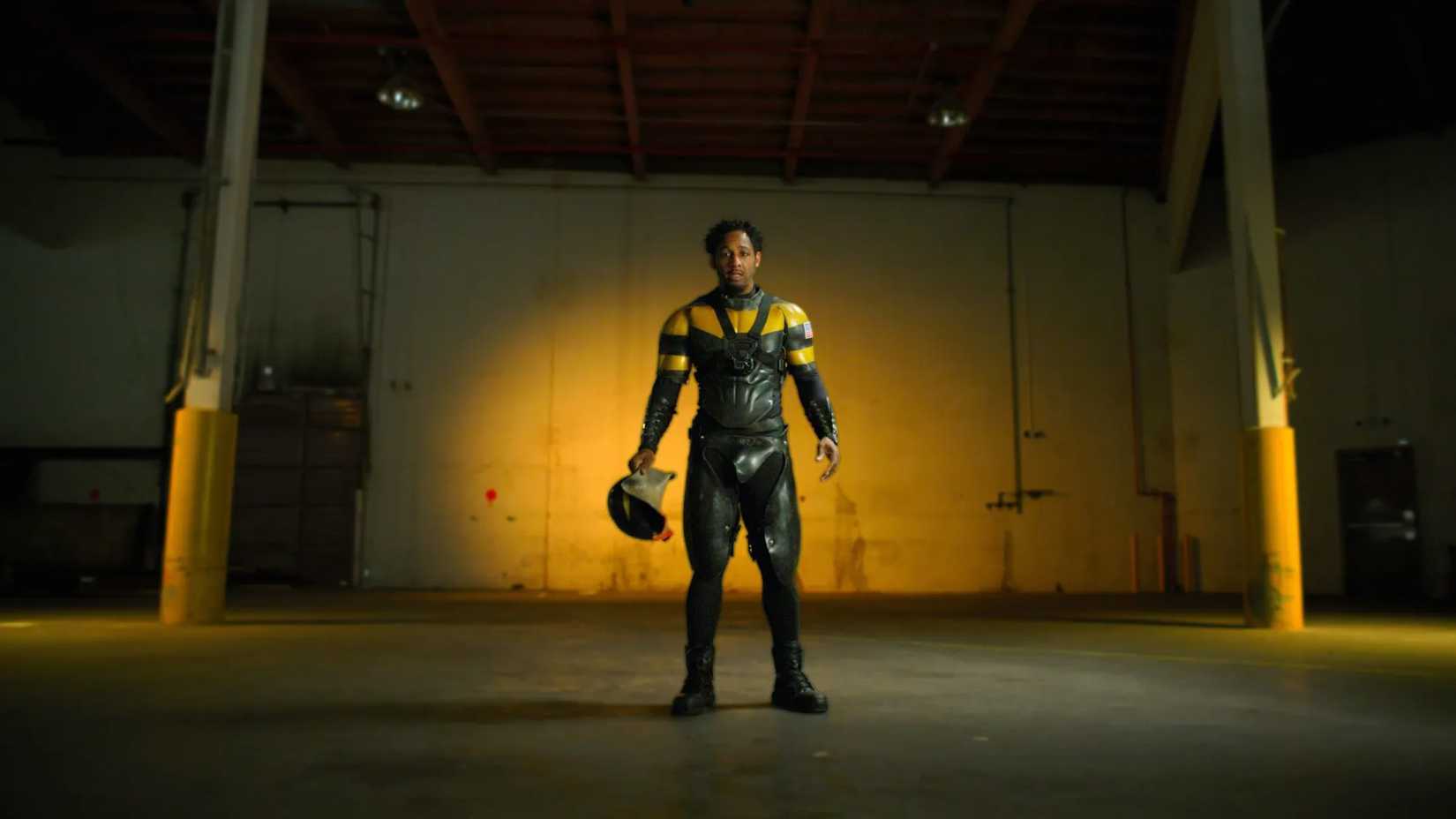 Phoenix Jones in a warehouse with his costume on and helmet off